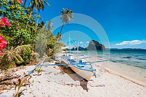 The Philippines`s Banca boat. Traditional fishing boat on beach in noon bright sun. El Nido,Palawan