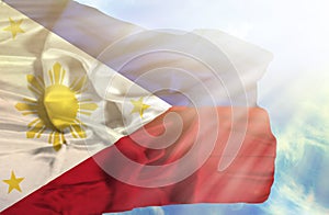 Phillipines waving flag against blue sky with sunrays