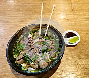 Pho Beef, Chicken Beef Meatballs RAMEN Traditional Vietnamese noodle soup with herbs in a bowl with chopsticks