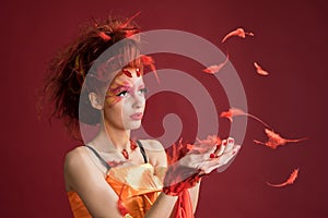 Phoenix. Young girl portrait and flying feathers. Woman holds a feather in hands.