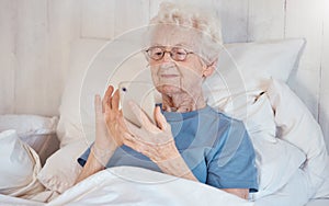 Phone, bed and senior woman in nursing home surfing internet, social media or nostalgic photographs with happy memories
