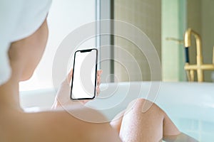 Phone blank screen display in woman hand, relax in bathtub with