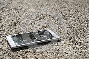 Phone with broken screen on asphalt. Someone dropped device.