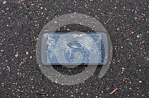 Phone with broken screen on asphalt. Someone dropped device