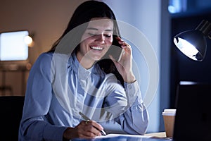 Phone call, book writing and business woman talking, chatting or speaking to contact in office at night. Technology