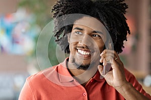 Phone Call. Closeup Of Smiling Millennial Black Man Talking On Cellphone Indoors