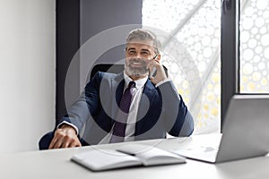 Phone Call. Smiling Mature Businessman In Suit Talking On Cellphone At Workplace