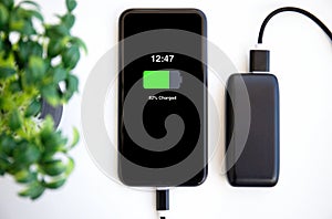 Phone with charged battery on the screen connected to powerbank