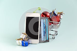 Phone with copy space, shopping cart with gifts, credit cards to buy online.