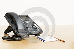 Phone on desk with notepad on wooden desk