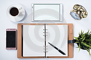 Phone, digital tablet, clock, plant, memo pad and blank notebook with on white flat lay.