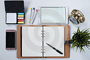 Phone, digital tablet, clock, plant, memo pad and blank notebook with on white flat lay.