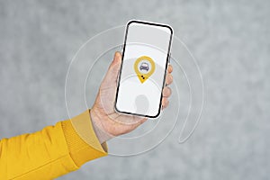 Phone display with Taxi icon on light background. Man holds a mockup smartphone in his hand close-up