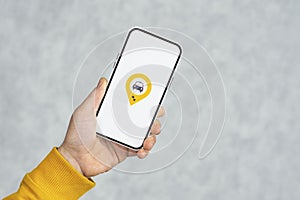 Phone display with Taxi icon on light background. Man holds a mockup smartphone in his hand close-up