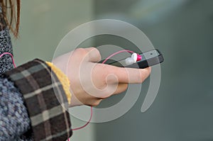 Phone in the girl`s hand, on which lies the earphone