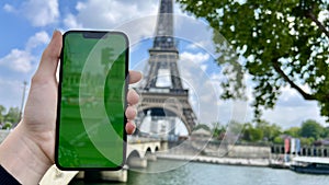 Phone with green Chromate screen on the background of the eiffel tower. in Paris using her cell phone in front of Eiffel