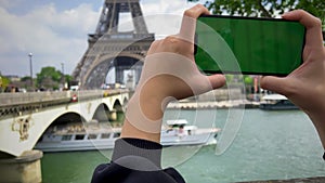 Phone with green Chromate screen on the background of the eiffel tower. in Paris using her cell phone in front of Eiffel