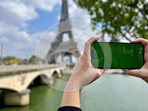 Phone with green Chromate screen on the background of the eiffel tower. in Paris using her cell phone in front of Eiffel