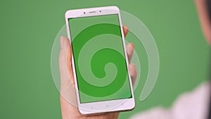 Phone in the hand close up isolated at green background. Phone screen is green chroma key, background chroma key green