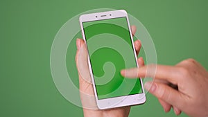 Phone in the hand close up isolated at green background. Phone screen is green chroma key, background chroma key green