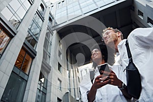 With phone in hands. Man with afrian american woman together in the city outdoors