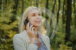 Phone happy outdoor. Blonde woman rejoicing and holding mobile phone in hands. Happy woman using smart phone. Work goals
