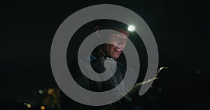 Phone, headlamp and man hiker at night, searching for directions to location of campsite. Map, navigation and light with