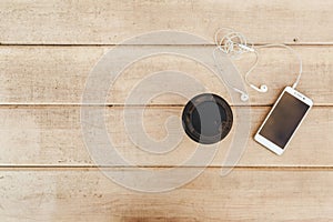 Phone with headphones and coffee on wood blank space