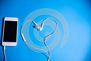 Phone and heart-shaped headphones on an isolated blue background