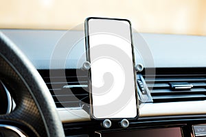 Phone holder attached to the ventilation grille in the vehicle and a phone with a white screen on it