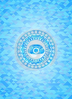 Phone icon inside realistic light blue emblem. Mosaic background