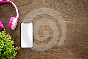 Phone with isolated screen on wooden table with headphones