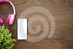 Phone with isolated screen on wooden table with headphones