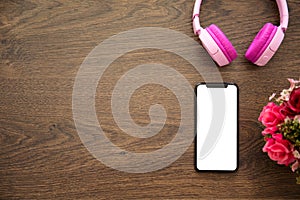 Phone with an isolated screen on wooden table with headphones