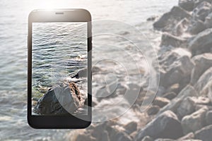 Phone layout on background of clear waters and a rocky beach photo