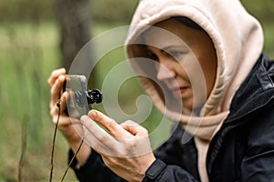 Phone lenses for macro photography. A woman holds a mobile phone with a macro attachment in her hands and takes pictures of plants