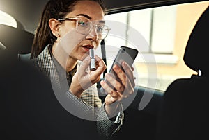 Phone, lipstick and a business woman in a car to travel in the city for work while multitasking. Face, mobile and makeup