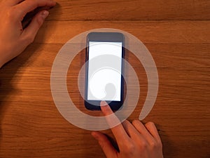 A phone lying in the dark on a wooden table.