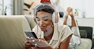 Phone, music headphones and happy woman on sofa in home, listen to audio and video app to relax. Smartphone, sound and