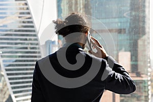 Confident young african businessman talk on phone by office window