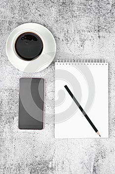 Phone notepad with pencil and coffee on a flat masonry. View from above
