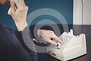 Phone old retro, old fashioned white telephone against green background, woman hand holding telephone cord in long