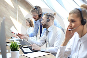 Phone operator working at call centre office helping hiss colleague