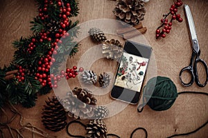 Phone with photo of rustic christmas wreath flat lay. Process of