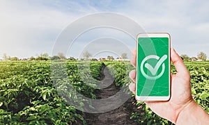 Phone with a quality mark on a farm plantation. Growing organic vegetables. Control permissible doses of harmful chemicals