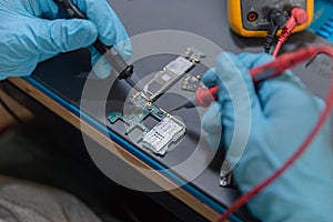 Phone repair concept a young electrical technician using an ammeter measuring the current in a circuit of an electronic device