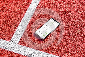Phone with running app concept on athletics field