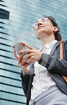 Phone, search and business woman in city from below for location and walking by a building or street. smartphone, social