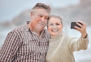 Phone, selfie and beach with a senior couple taking a photograph while on holiday or vacation travel together. Mobile