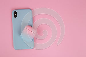 Phone in a silicon case and a case for headphones on a pink background with copy space. Stylish phone and headphone case. Woman